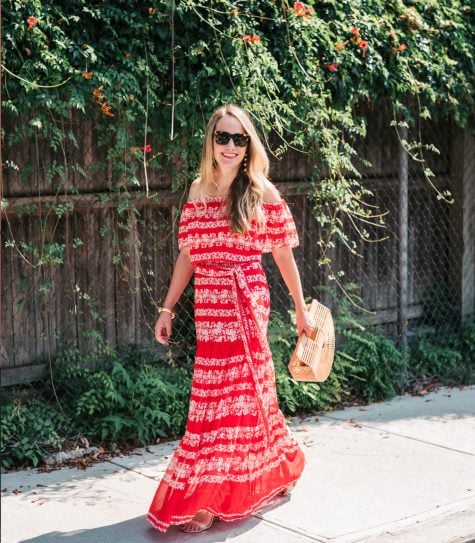 spray tan tips for an even tan like this girl in a red dress and shades with a fence and green leaves in the background