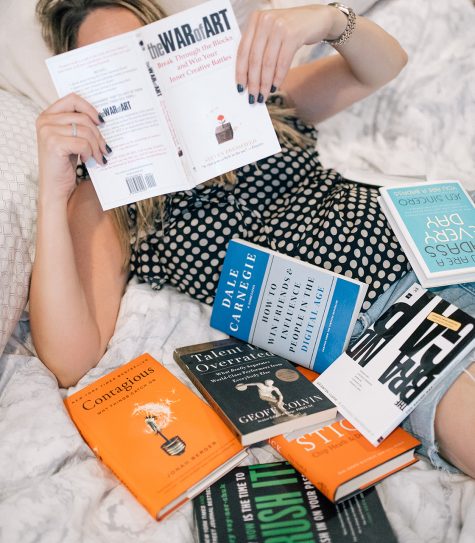 Grace lays in a pile of business books